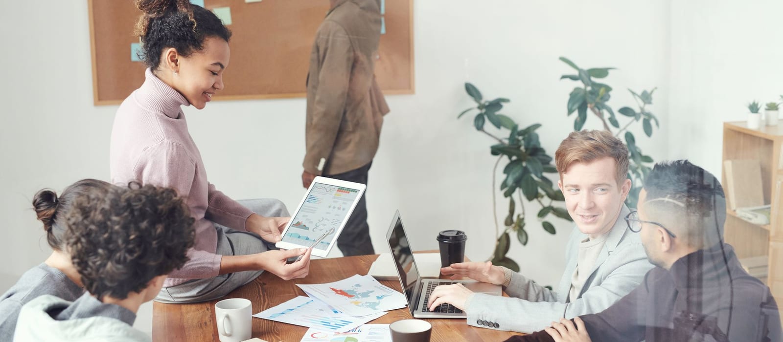 A small-business team of coworkers meeting around a table with laptops