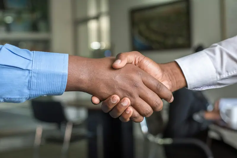 Two people shaking hands across an office desk