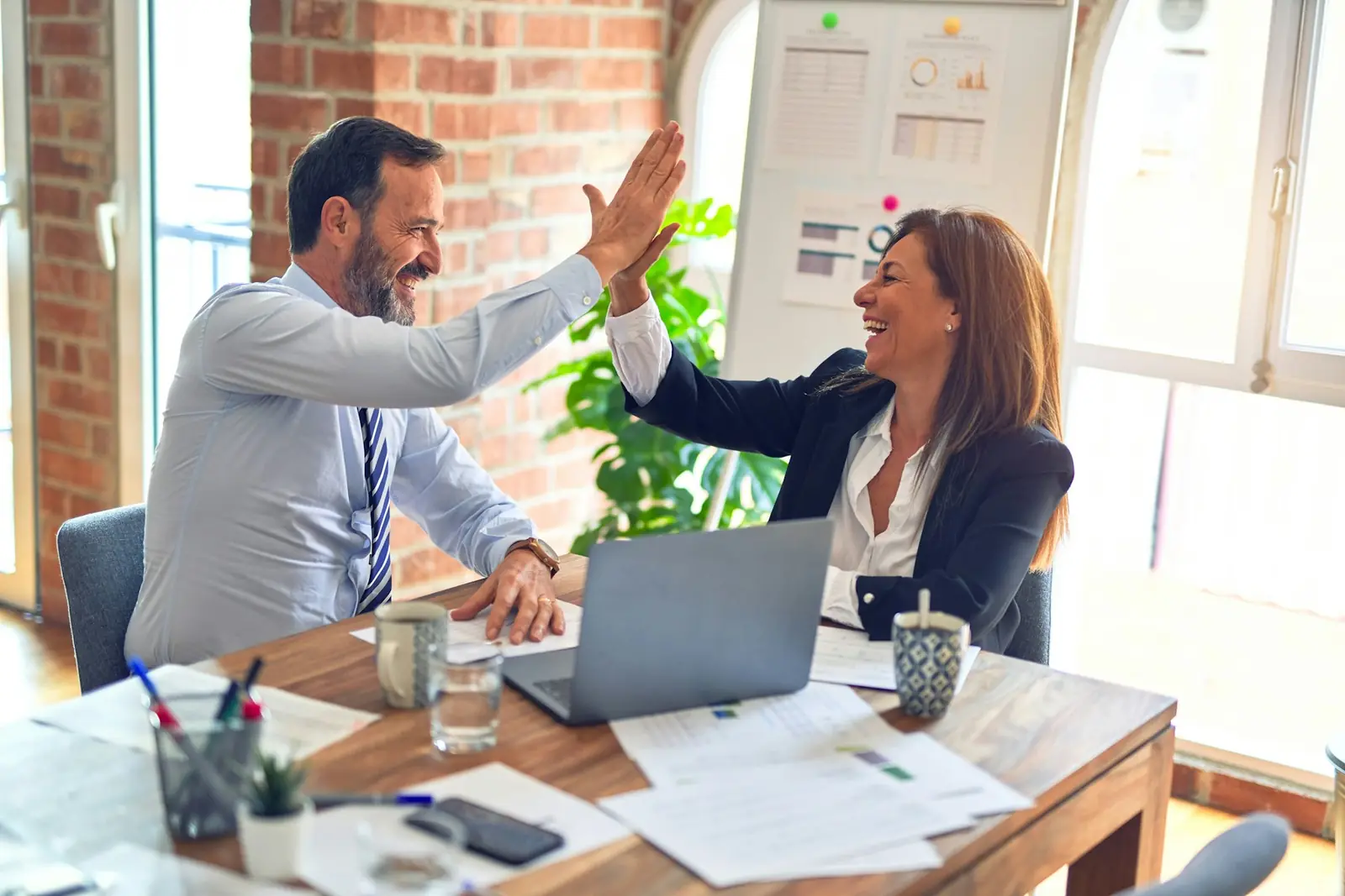 Two coworkers celebrating at an office desk